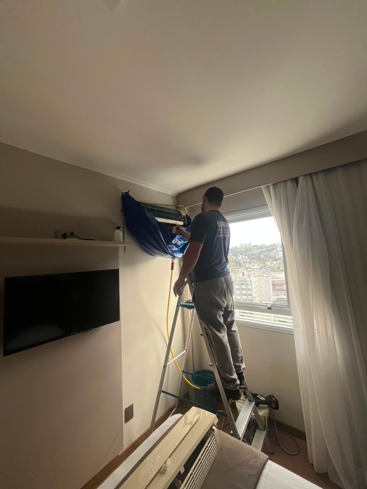 Técnico realizando higienização de ar-condicionado